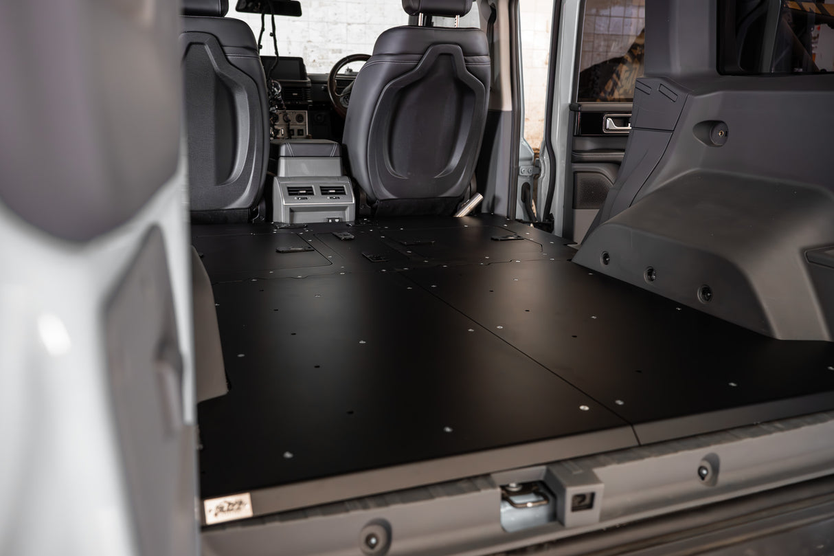 Buzz Overland Buzz Base for INEOS Grenadier, a 36kg 5052 aluminium deck replacing 56kg factory seats, with access hatches for stealth overlanding and roof conversions.