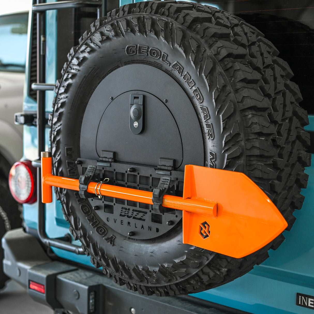 Buzz Overland Spare Wheel Storage cubby with black Molle panel, Geolander tire with orange GP Factor Shovel on a vehicle